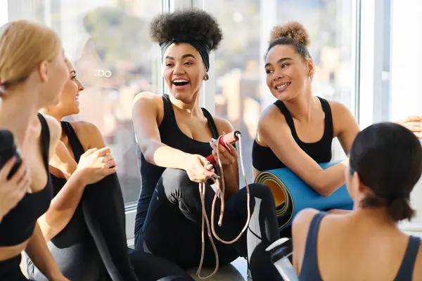 Grupo de felices jóvenes interracial mujeres en activo desgaste charlando después del entrenamiento en pilates estudio - foto de stock