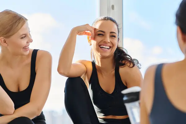 Sonnenlicht im Gesicht einer fröhlichen brünetten Frau in aktiver Kleidung, die nach dem Training mit ihren Freundinnen lacht — Stockfoto