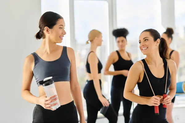 Cheerful multicultural female friends in active wear smiling at each other after pilates workout — Stock Photo