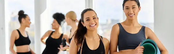 Banner of happy diverse female friends in active wear smiling at camera after pilates workout — Stock Photo