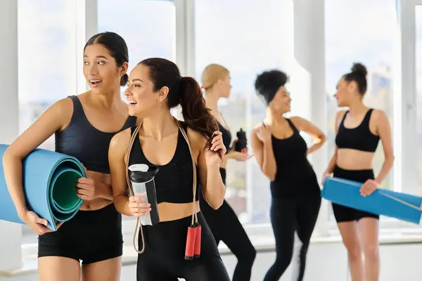 Focus on joyful diverse female friends in active wear smiling and looking away after pilates workout — Stock Photo