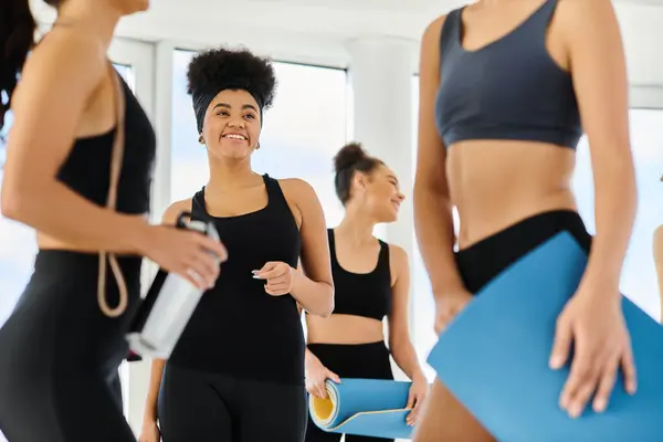 Foco na mulher americana africana alegre olhando para seus amigos após o treino de pilates em estúdio — Fotografia de Stock