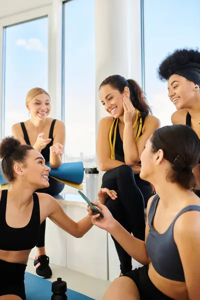 Groupe de cinq femmes multiculturelles en vêtements de sport bavarder après l'entraînement dans pilates studio — Photo de stock