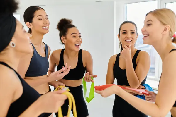 Group of happy diverse sportswomen holding resistance bands and talking after pilates workout — Stock Photo