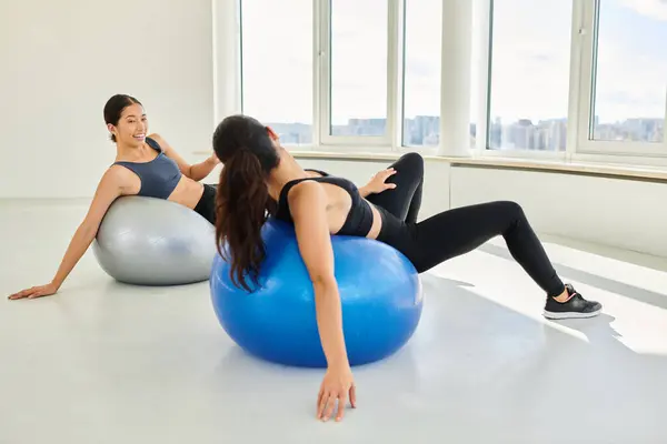 Happy diverse women exercising on fitness balls during pilates class, female friends and sport — Stock Photo