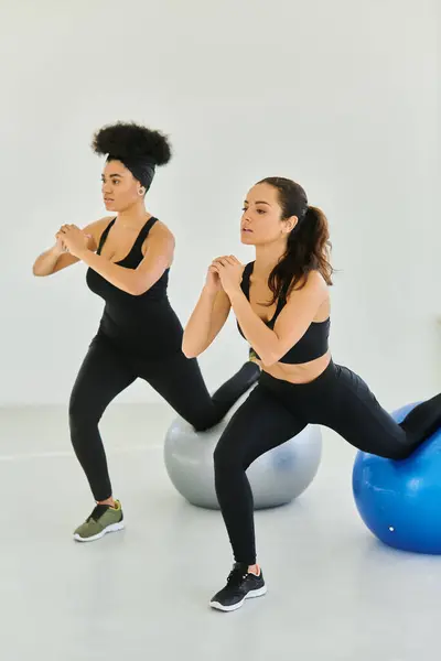 Deux amies diverses faisant de l'exercice sur des balles de fitness pendant le cours de pilates, motivation et force — Photo de stock