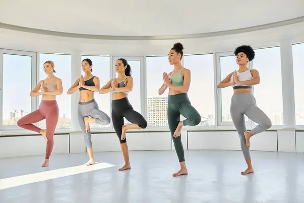 Groupe de jeunes cinq femmes diverses en vêtements de sport pratiquant l'exercice de yoga ensemble en studio — Photo de stock
