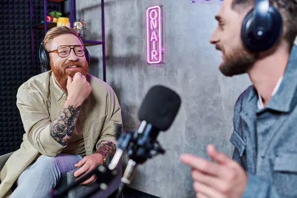 Bearded handsome interviewer and his guest with headphones in studio discussing questions, podcast — Stock Photo