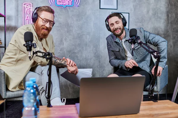 Gut aussehende, stylische Männer mit Bart und Kopfhörer, die während eines Podcasts im Studio Fragen diskutieren — Stockfoto