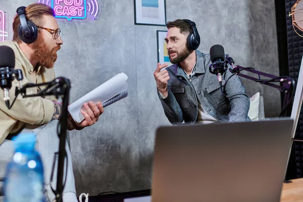 Gut aussehende, stylische Männer mit Bart und Kopfhörer, die während eines Podcasts im Studio Fragen diskutieren — Stockfoto