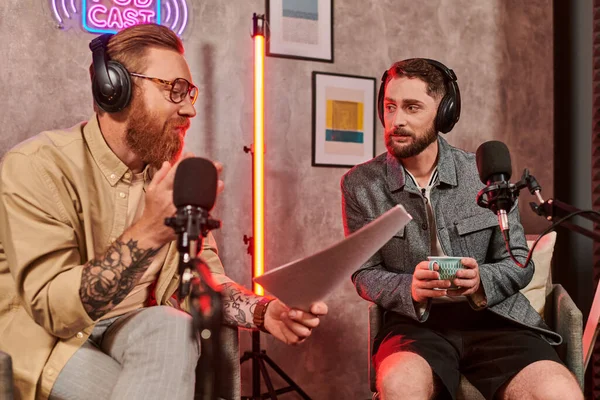 Entrevistador guapo con atuendo casual discutiendo preguntas con su joven invitado durante el podcast - foto de stock