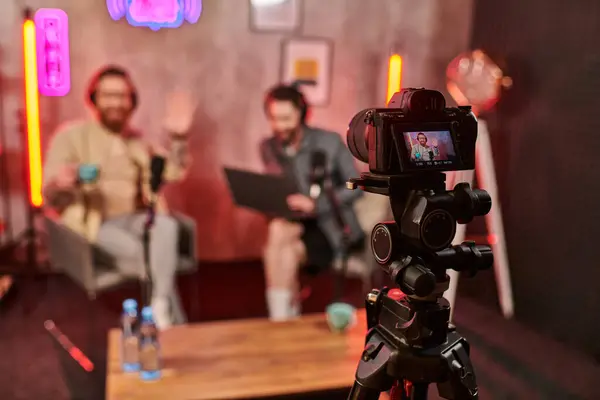 Focus sur caméra filmant hommes flous élégants avec barbe dans les écouteurs discuter des questions — Photo de stock