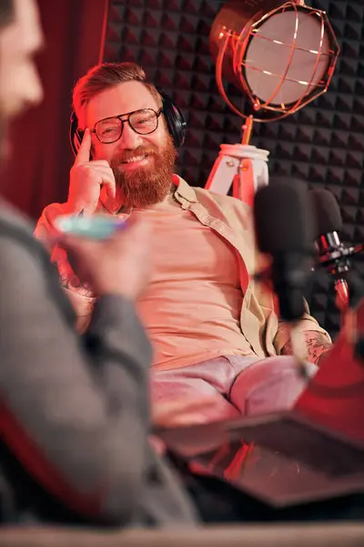 Hombres dedicados en trajes cómodos con café y auriculares durante su discusión en podcast - foto de stock