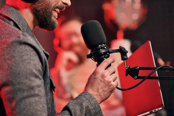 Обрізаний зосереджений вид бородатого чоловіка з мікрофоном зі своїм розмитим інтерв'юером на подкасті — стокове фото