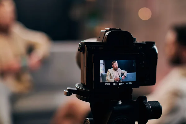 Focus on camera filming stylish blurred man with beard in elegant attire discussing questions — Stock Photo