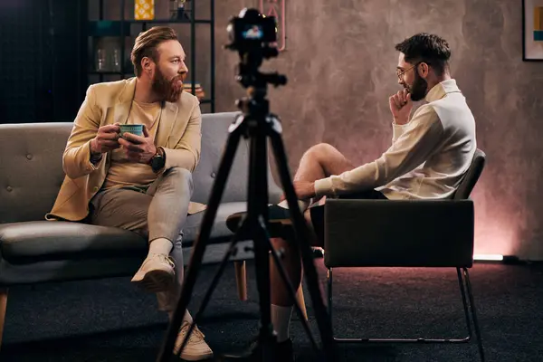 Hombres dedicados con barbas en trajes elegantes sentados y discutiendo preguntas durante la entrevista - foto de stock