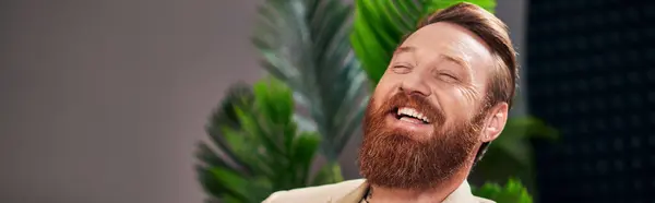 Guapo hombre alegre con barba en elegante atuendo riendo durante la entrevista, mientras que en el estudio, pancarta - foto de stock