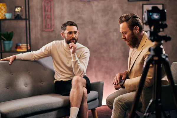 Hombres barbudos de buen aspecto en elegantes trajes elegantes sentado y discutiendo preguntas de la entrevista - foto de stock