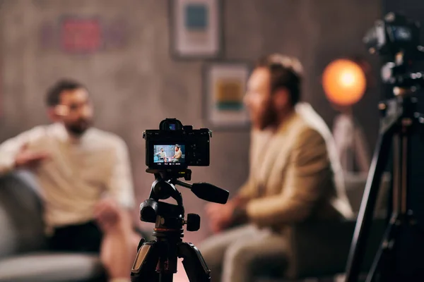 Focus on camera filming stylish blurred men with beards in elegant attires discussing questions — Stock Photo