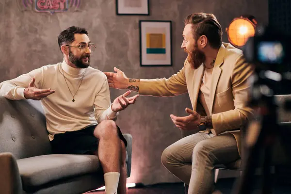 Dos hombres barbudos atractivos en elegantes trajes elegantes sentados y discutiendo preguntas de la entrevista - foto de stock