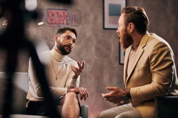 Dos hombres barbudos atractivos en elegantes trajes elegantes sentados y discutiendo preguntas de la entrevista - foto de stock