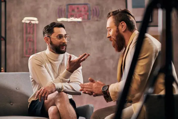 Dos hombres barbudos guapos en elegantes trajes elegantes sentado y discutiendo preguntas de la entrevista - foto de stock