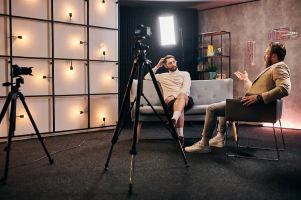 Dos hombres elegantes con barbas con estilo elegante sentado y discutiendo preguntas de la entrevista en el estudio - foto de stock