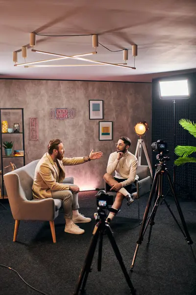 Hombres elegantes atractivos en ropa elegante sentado y discutiendo preguntas de la entrevista en el estudio - foto de stock