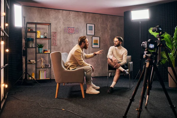 Attraenti uomini eleganti in abiti eleganti seduti e discutendo domande intervista in studio — Foto stock