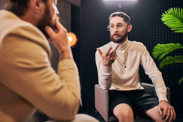 Engagierte elegante Männer in Debonair-Klamotten sitzen im Studio und diskutieren Interviewfragen — Stockfoto