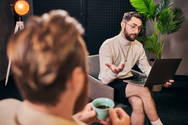 Красивые шикарные мужчины в элегантных одеждах с кофе и ноутбуком обсуждают вопросы интервью — стоковое фото