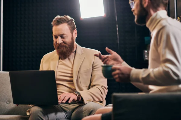 Deux joyeux hommes attrayants en tenues élégantes avec café et ordinateur portable discuter des questions d'entrevue — Photo de stock