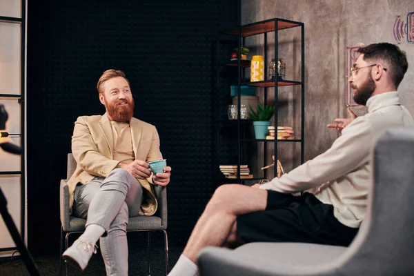 Alegres hombres guapos en ropa elegante con café discutir preguntas durante la entrevista - foto de stock