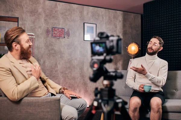 Allegri uomini barbuti eleganti in abiti eleganti che parlano attivamente durante la loro intervista in studio — Foto stock