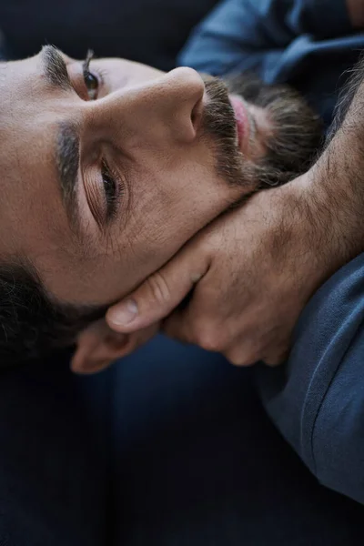 Depressiver bärtiger Mann in Freizeitkleidung liegt bei Zusammenbruch auf Sofa, Bewusstsein für psychische Gesundheit — Stockfoto