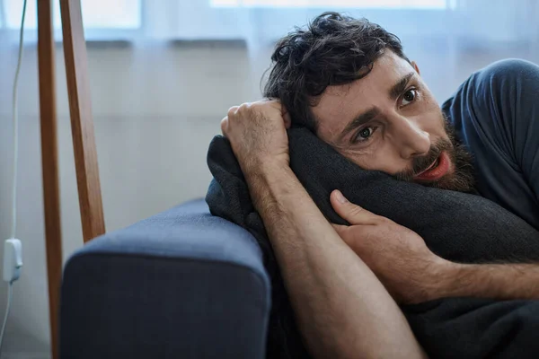 Frustrated bearded man in casual home wear lying on sofa during breakdown, mental health awareness — Stock Photo