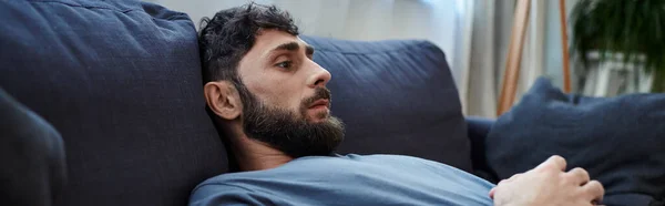 Ängstlicher verzweifelter Mann, der während einer depressiven Episode auf dem Sofa liegt, Bewusstsein für psychische Gesundheit, Transparent — Stockfoto