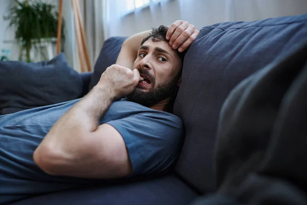 Depressiver hoffnungsloser Mann in kuscheliger Hauskleidung, der während eines psychischen Zusammenbruchs auf dem Sofa liegt, Psychotherapie — Stockfoto