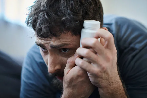 Verzweifelter Mann mit Tabletten in der Hand während depressiver Episode mit Selbstverletzungen, Bewusstsein für psychische Gesundheit — Stockfoto