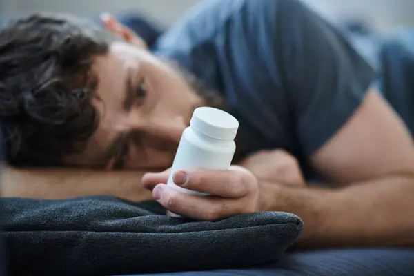 Verzweifelter Mann mit Tabletten in der Hand während depressiver Episode mit Selbstverletzungen, Bewusstsein für psychische Gesundheit — Stockfoto