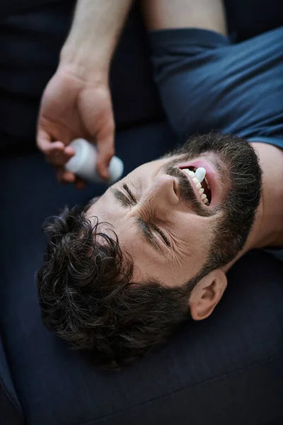 Homem deprimido emocional com barba tomando pílulas durante episódio depressivo, consciência de saúde mental — Fotografia de Stock
