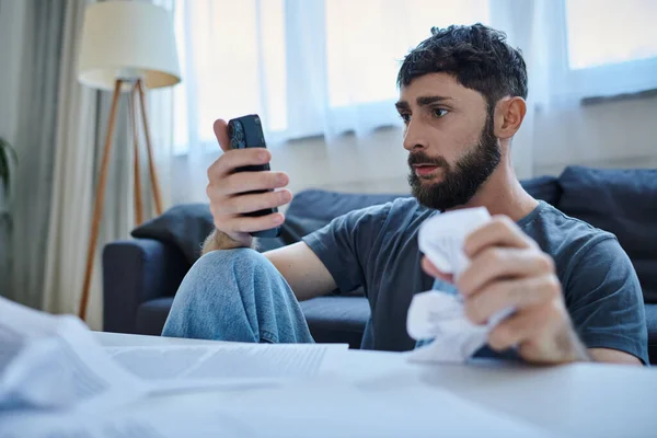 Deprimido hombre que sufre mirando a su teléfono inteligente durante el episodio depresivo, salud mental - foto de stock