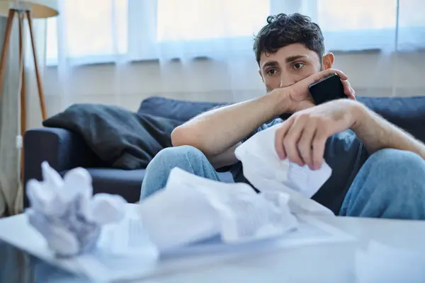 Homme malade frustré en tenue décontractée avec téléphone et papiers pendant la dépression, sensibilisation à la santé mentale — Photo de stock