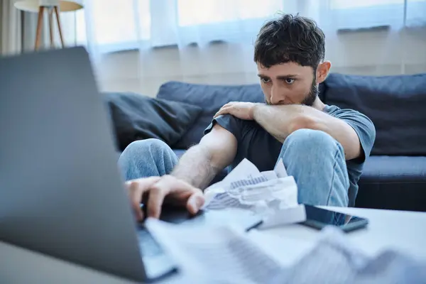 Depressiver Mann mit Bart in Freizeitkleidung, der während des Zusammenbruchs auf seinen Laptop schaut, psychische Gesundheit — Stockfoto