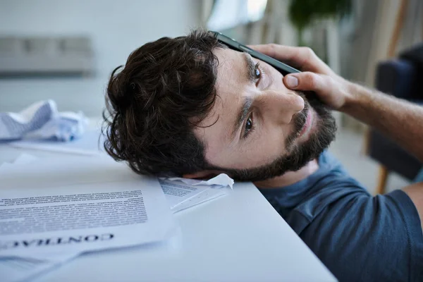 Depressed man talking by phone next to table with contract during breakdown, mental health awareness — Stock Photo
