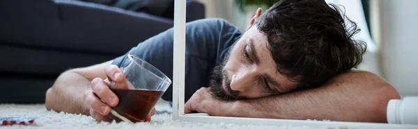Homme déprimé buvant de l'alcool et regardant des pilules pendant l'épisode dépressif, santé mentale, bannière — Photo de stock