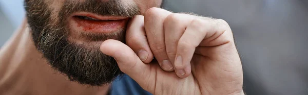 Visão cortada do homem ansioso com barba mordendo os lábios até o sangue durante o episódio depressivo, banner — Fotografia de Stock