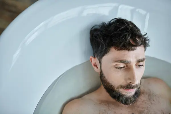 Depresso uomo frustrato con la barba sdraiato nella vasca da bagno durante il crollo, consapevolezza della salute mentale — Foto stock
