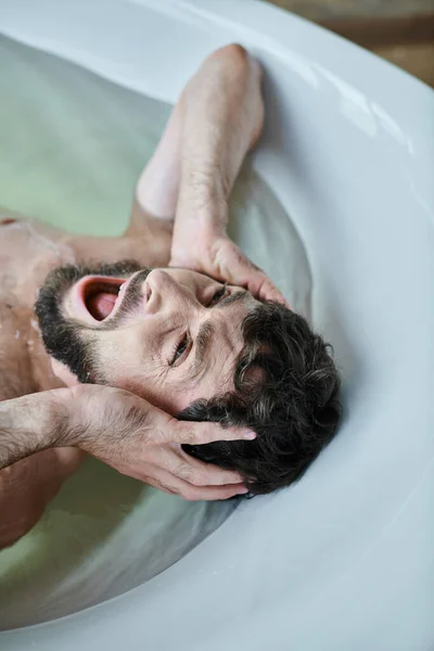 Uomo traumatizzato emotivo sdraiato nella vasca da bagno e urlando durante il crollo, consapevolezza della salute mentale — Foto stock