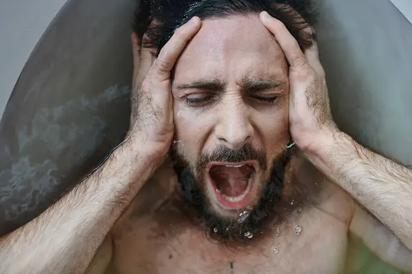 Hombre traumatizado emocional acostado en la bañera y gritando durante la ruptura, conciencia de salud mental - foto de stock
